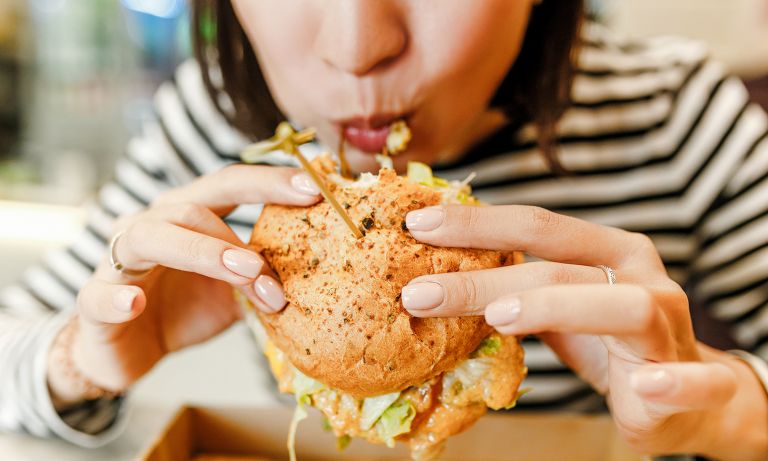 young woman eating fast food chicken sandwich 768